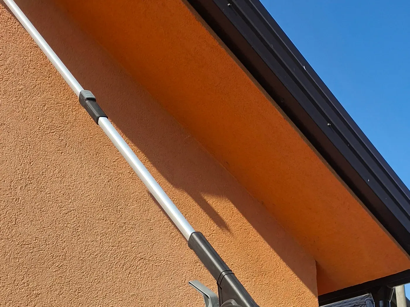 Teleskopski alat na fasadi tokom vanjskog čišćenja.